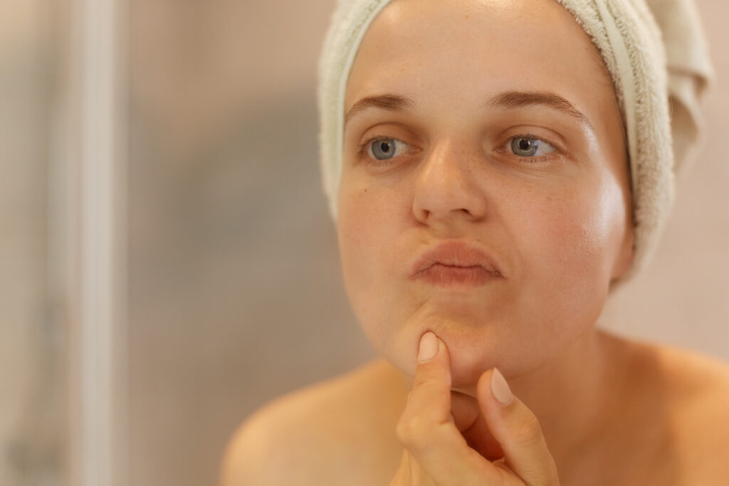 Femme qui se regarde dans le miroir avec la peau sèche